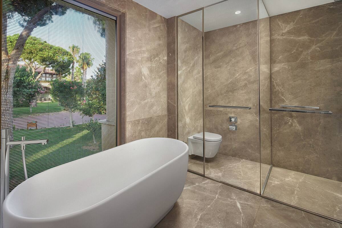 A modern bathroom with a freestanding bathtub, a glass-enclosed shower, and a toilet.