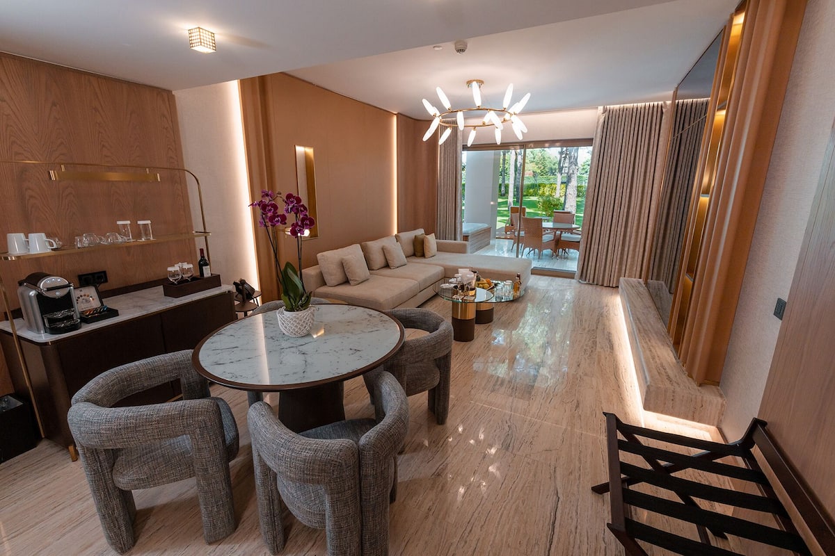 A modern hotel room with a dining area, a sofa, and a coffee station.