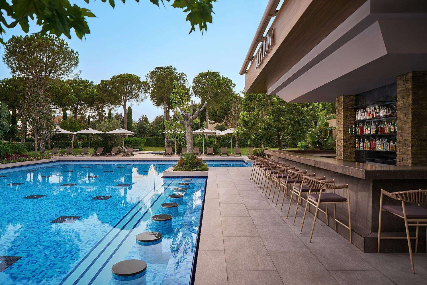 Une piscine avec des chaises longues et un espace bar.
