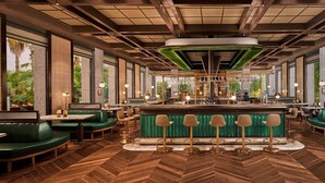 A spacious restaurant with green booths and tables, a central bar area, and large windows offering views of greenery. - Gloria Serenity Resort - All Inclusive (Serik)