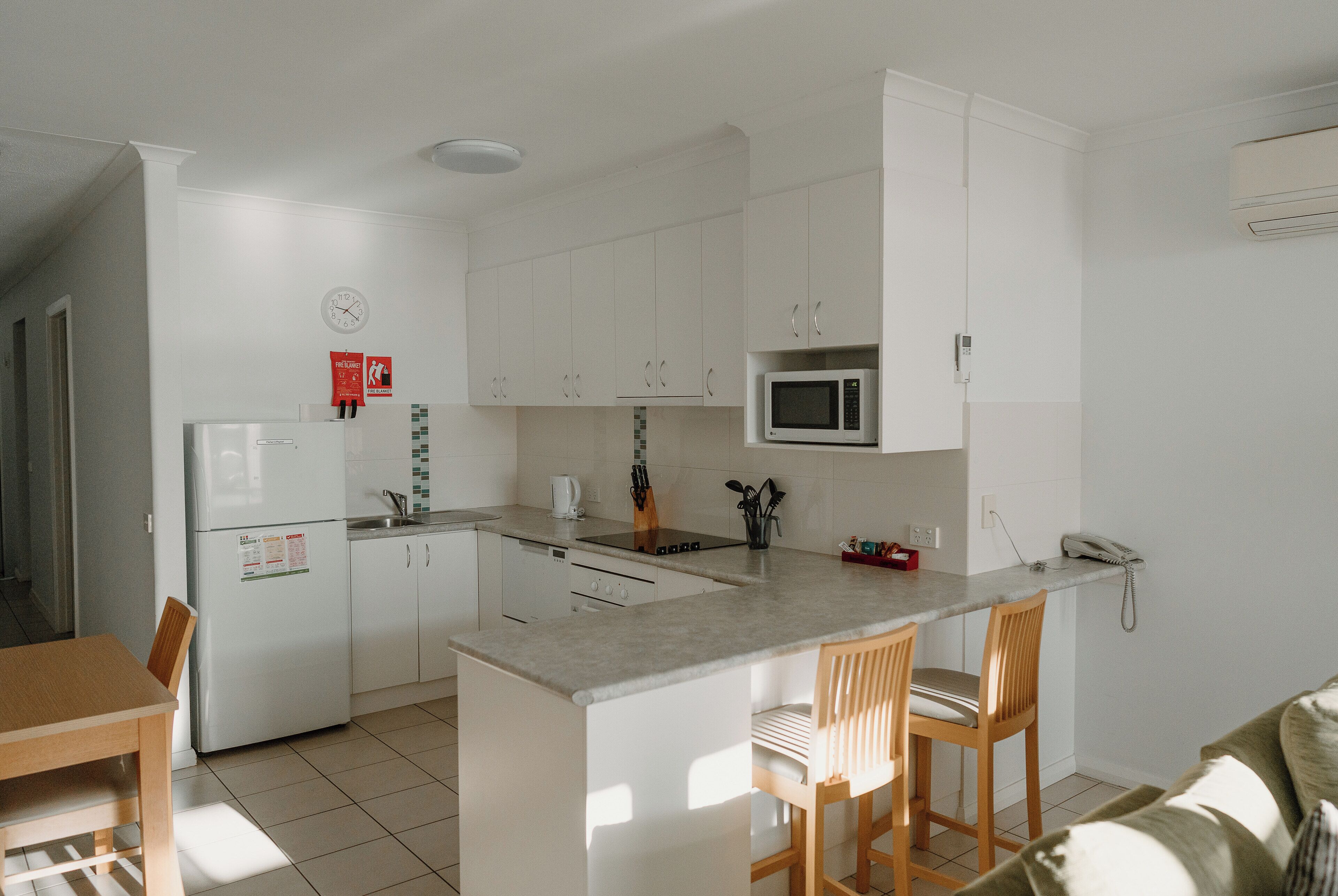 Una cocina moderna con armarios blancos, microondas integrado y una isla central con taburetes de bar.