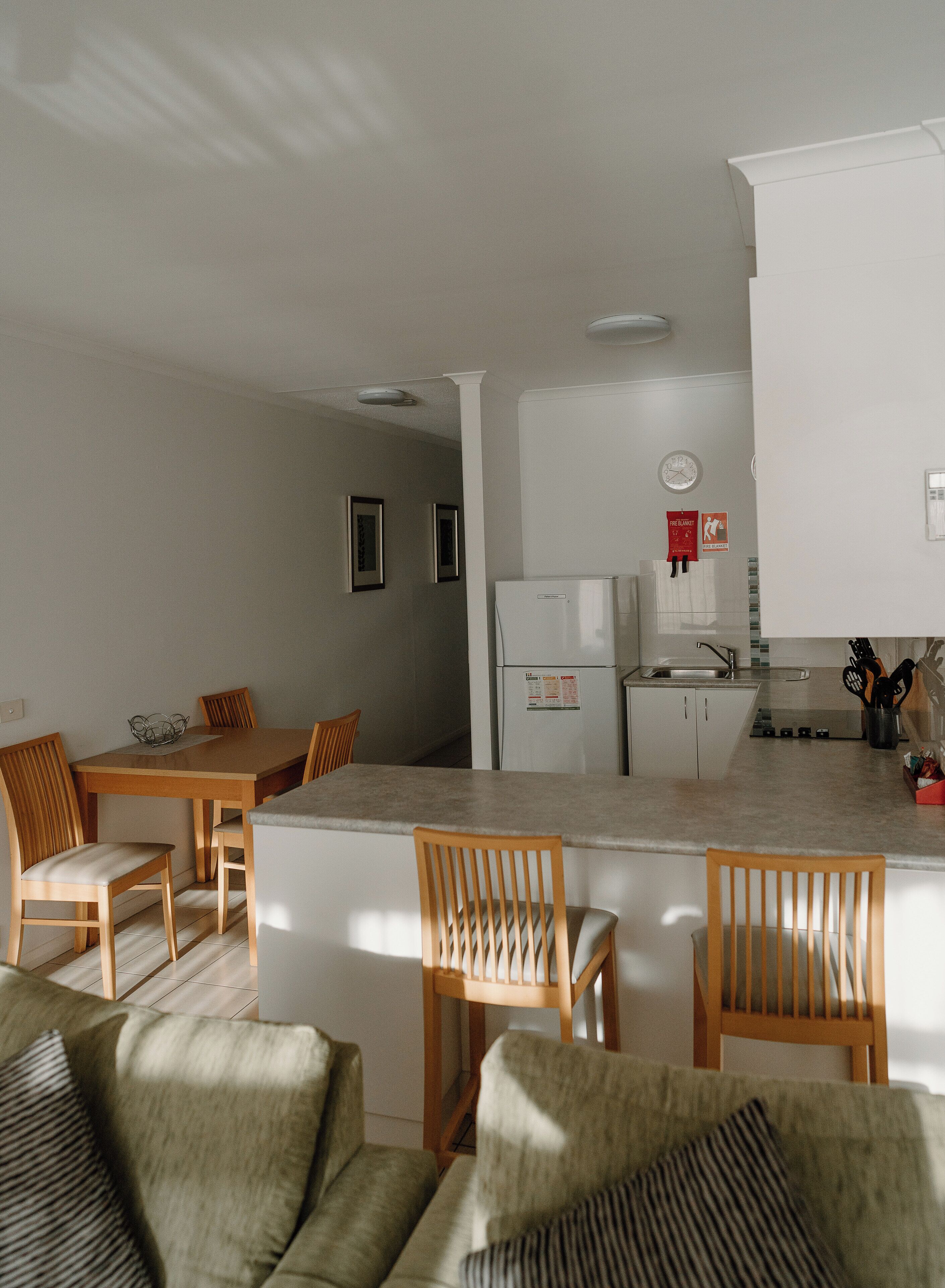 A modern kitchen with white cabinets, a refrigerator, and a dining area with wooden chairs and a table.