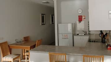 Una cocina moderna con armarios blancos, un refrigerador y un comedor con sillas de madera y una mesa.
