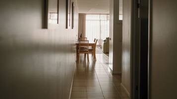 A hallway with a dining area at the end, featuring a table and chairs.