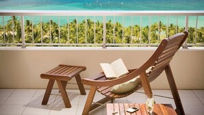 A balcony with a wooden chair and table, a book, and a glass of water.