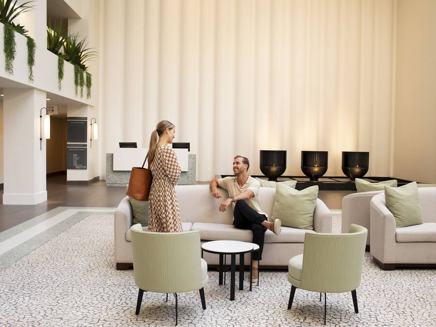 A modern lobby with a seating area, a reception desk, and a staircase.