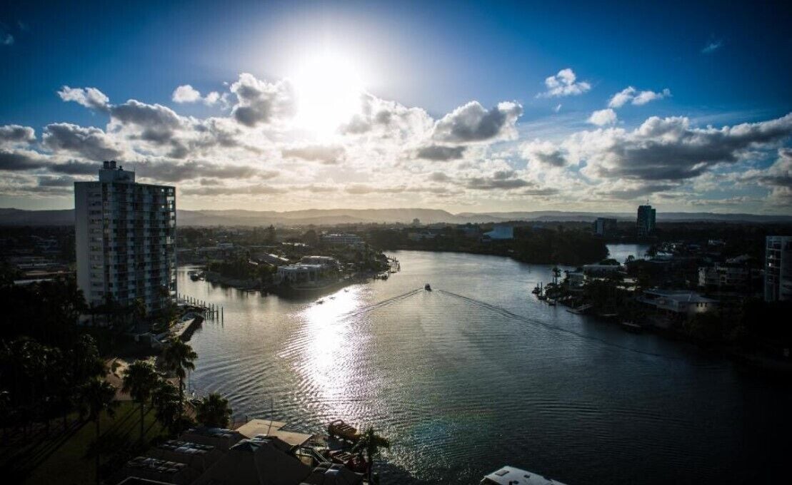 A river with a bridge, surrounded by buildings and a clear sky.