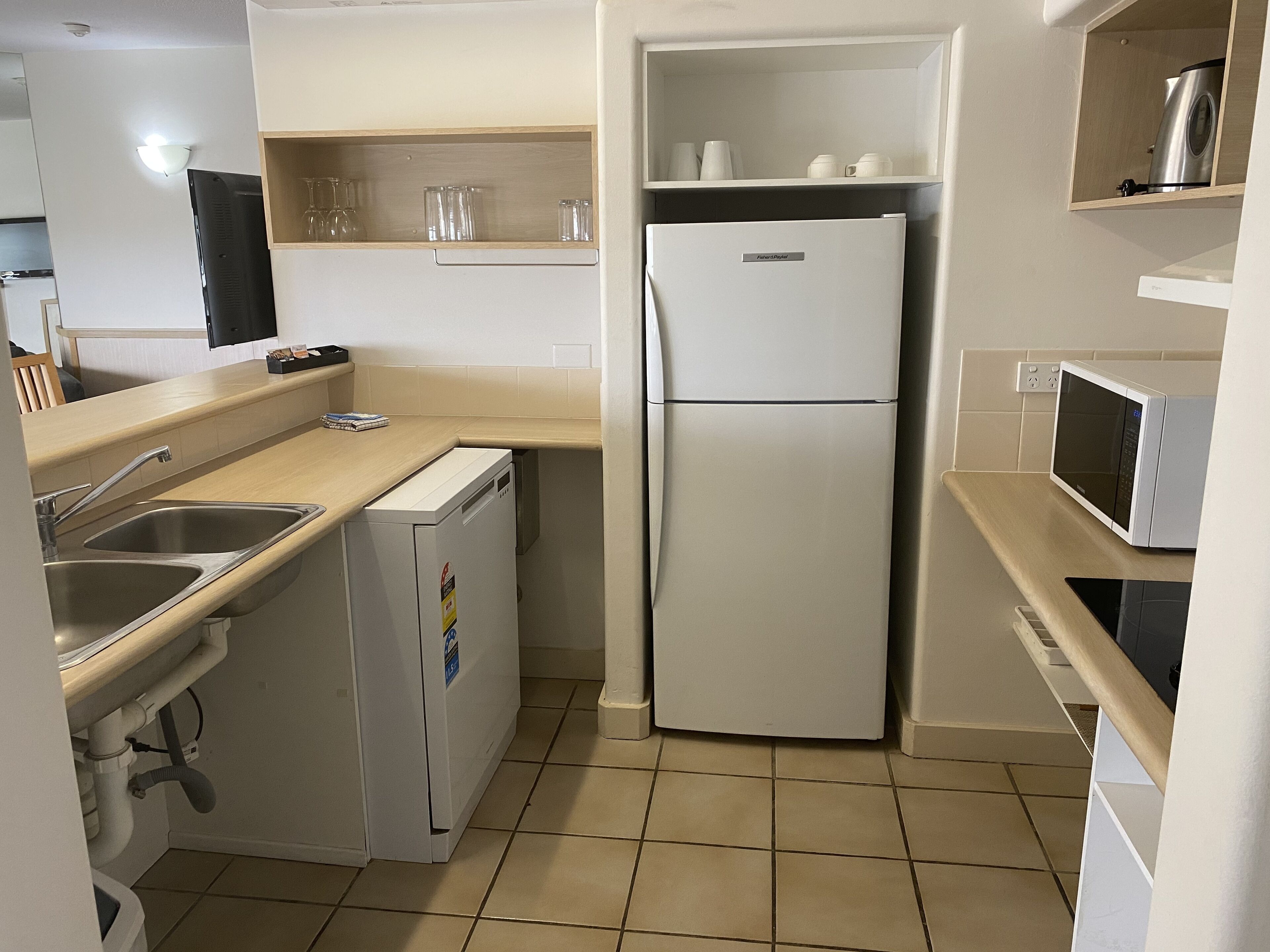 A compact kitchen with a refrigerator, microwave, and sink.