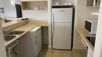A compact kitchen with a refrigerator, microwave, and sink.