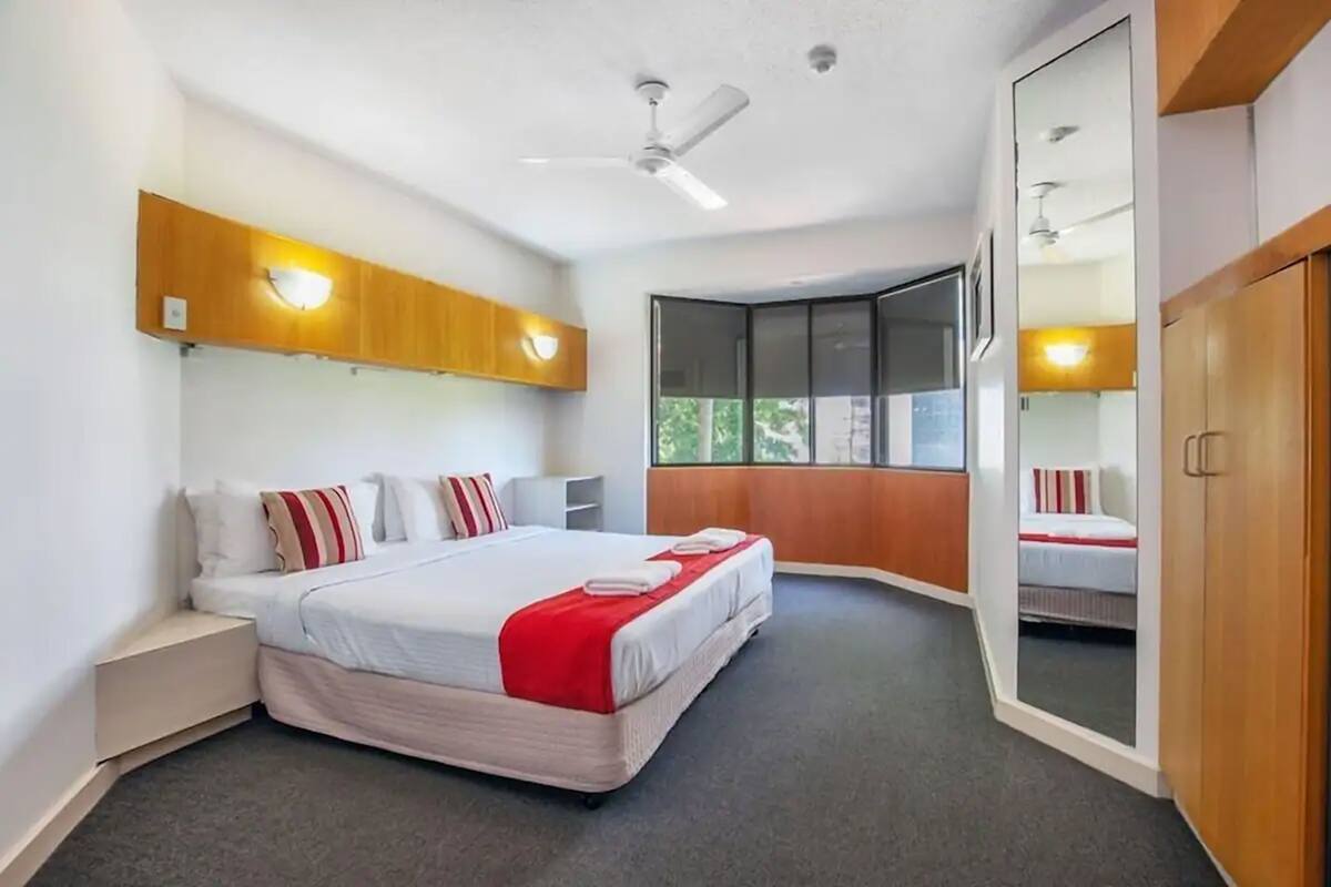Un dormitorio moderno con una cama grande, un ventilador de techo y una ventana con vistas.