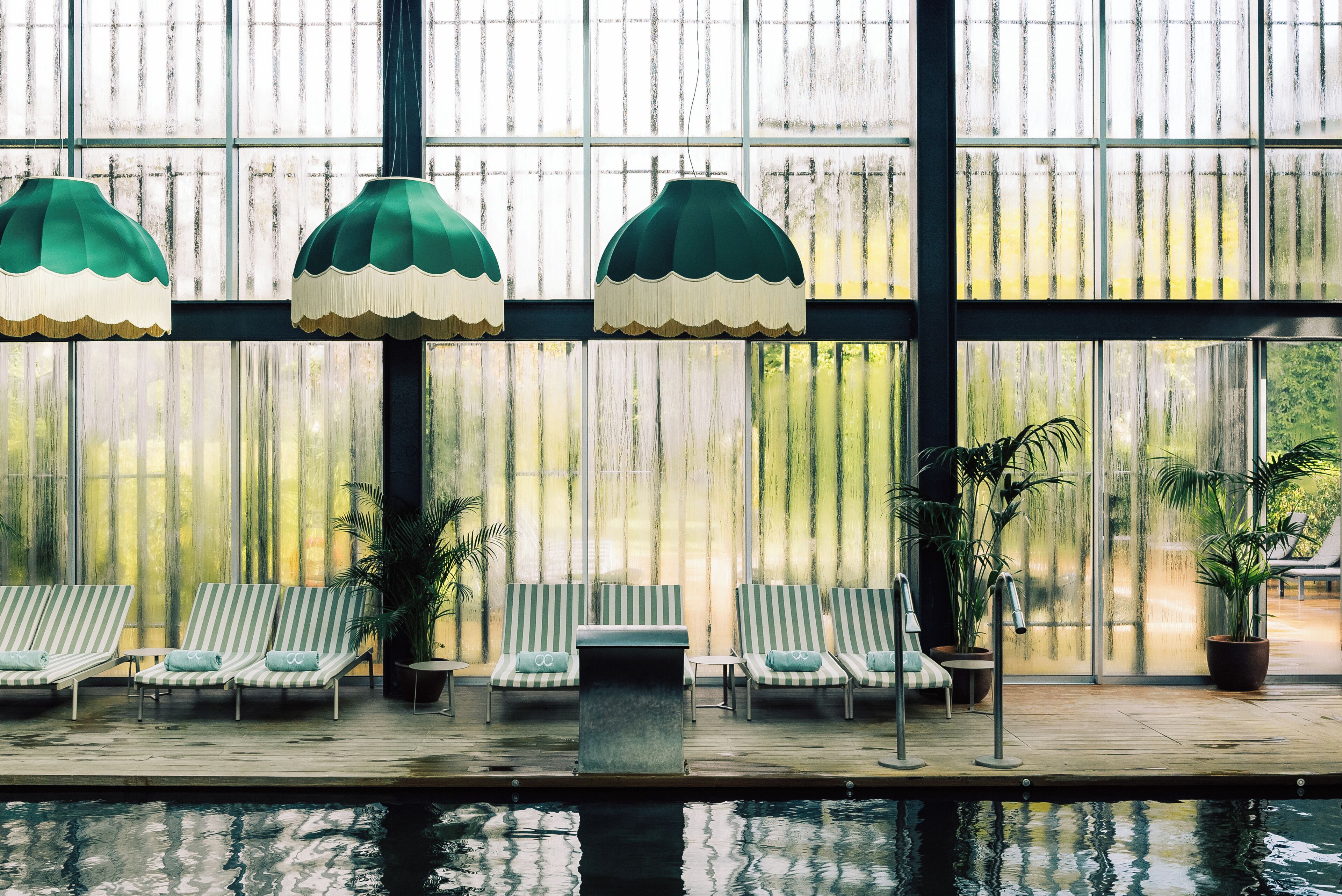 A poolside area with striped lounge chairs and hanging lamps.