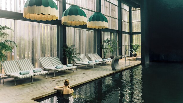 Una piscina interior con sillones de descanso y ventanas amplias.
