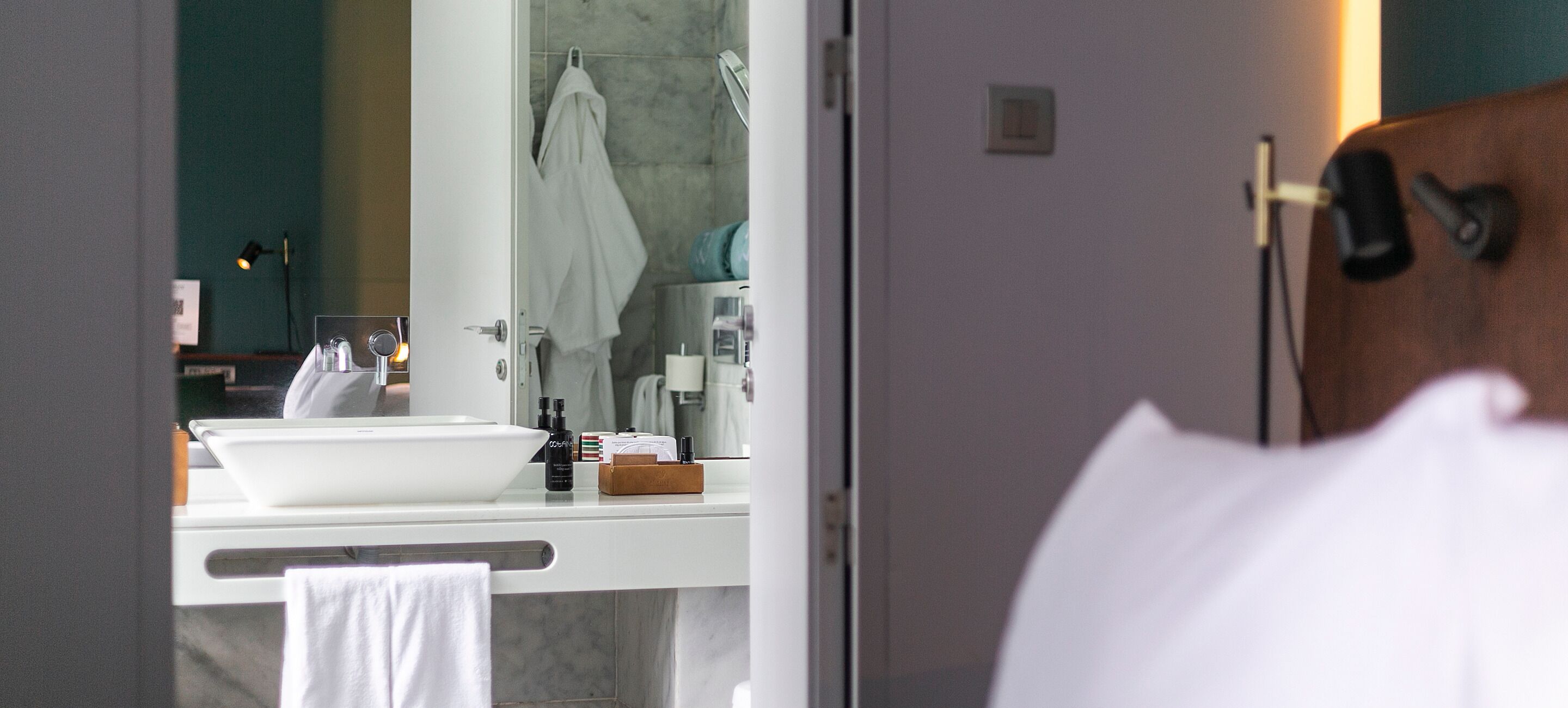 A bathroom with a white sink, mirror, and towel rack.