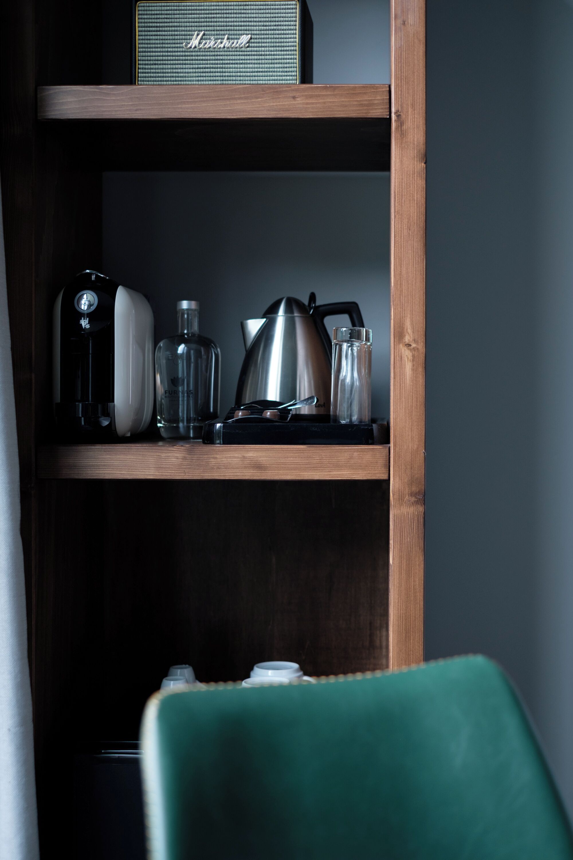 En træhylde med en Marshall-forstærker, en kaffemaskine, en elkedel og et glas.