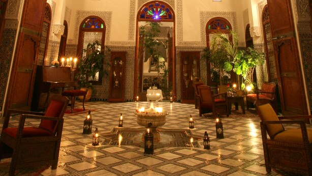 Un lobby lujoso con detalles de azulejos ornamentales, un techo alto y un balcón con vistas al patio.