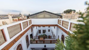 Un patio con un área central abierta, rodeado de muros blancos con balcones de madera y ventanas arqueadas.