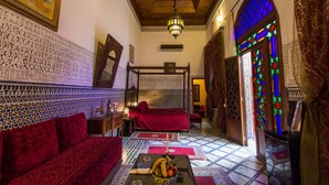 Una habitación tradicional marroquí con cama, sofá y un muro decorativo.