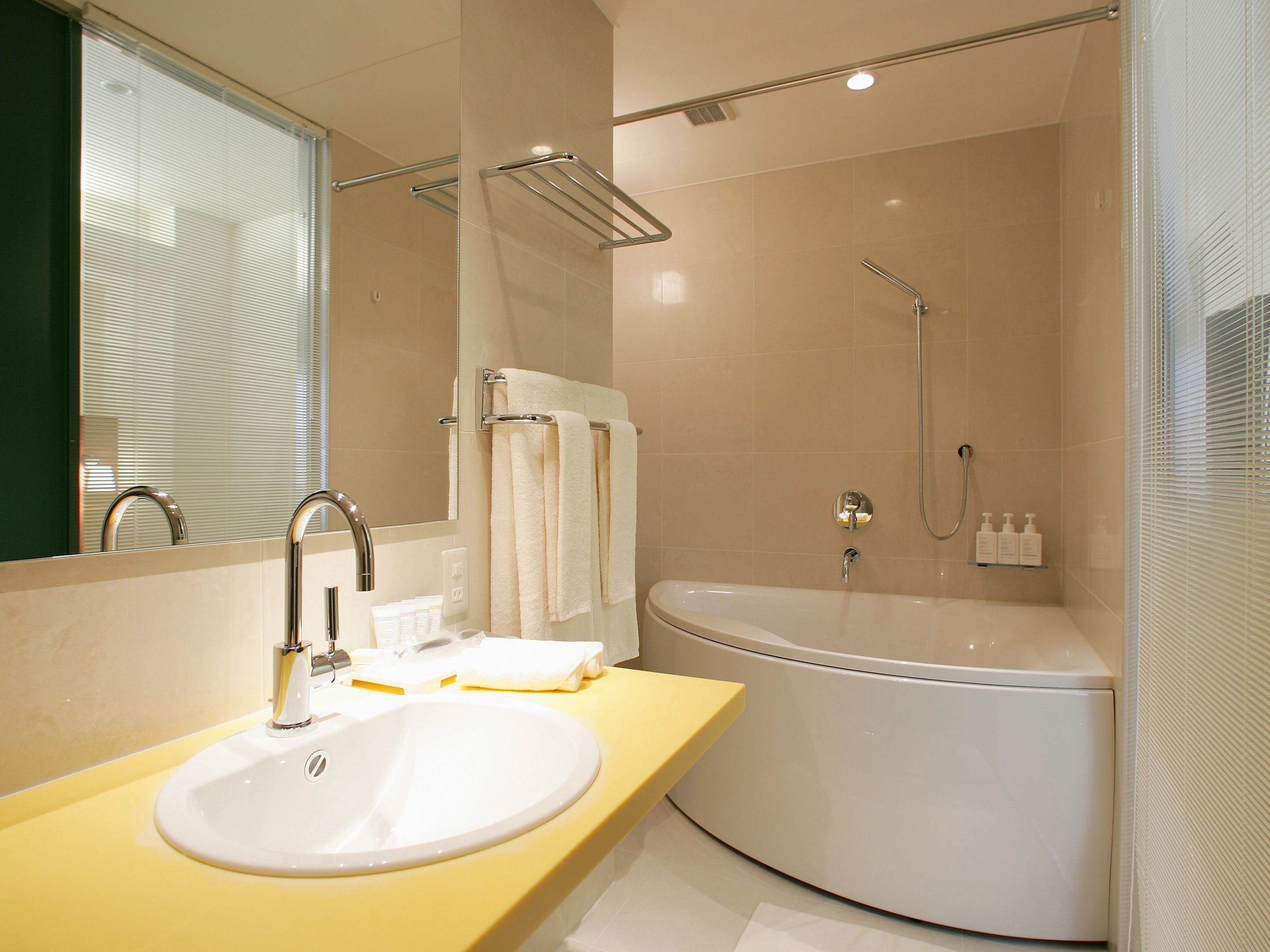 Ein modernes Badezimmer mit einem weißen Waschbecken, einer gelben Arbeitsplatte und einer großen Badewanne.