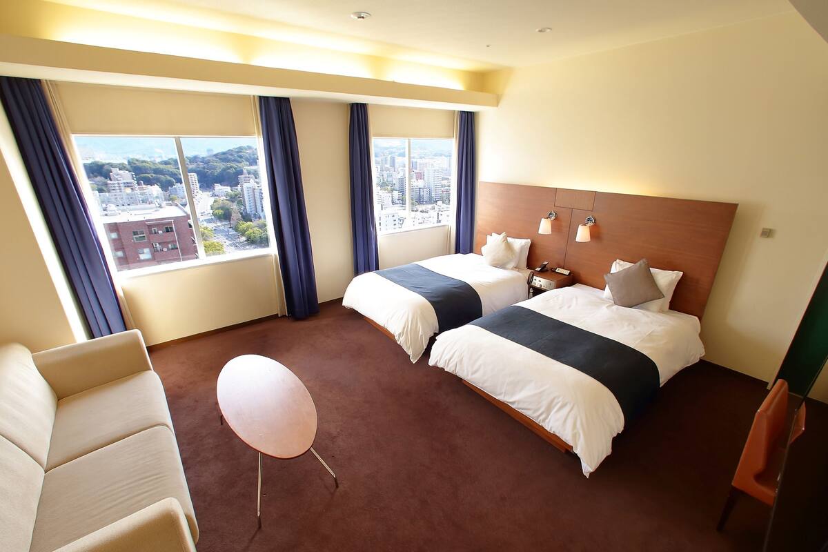 Una habitación de hotel con dos camas, una silla, un globo y vistas a la ciudad.