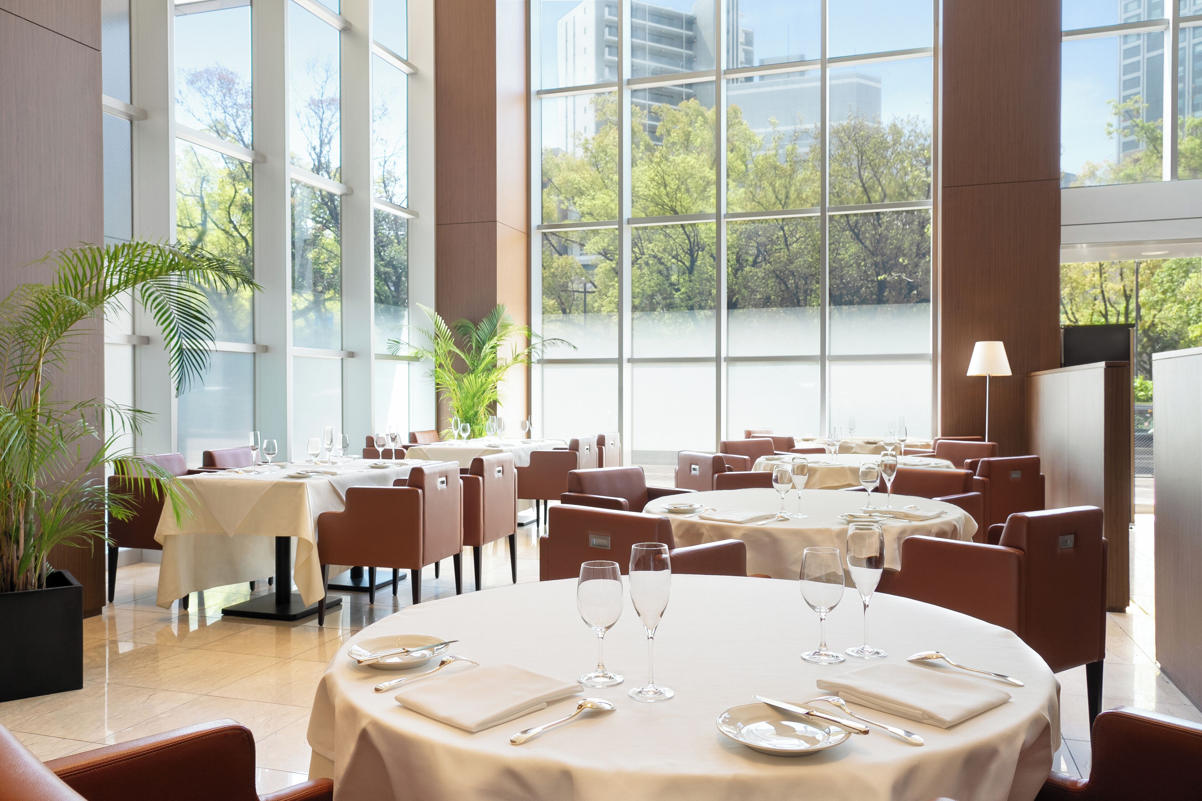 A spacious restaurant with large windows, multiple dining tables, and comfortable seating.