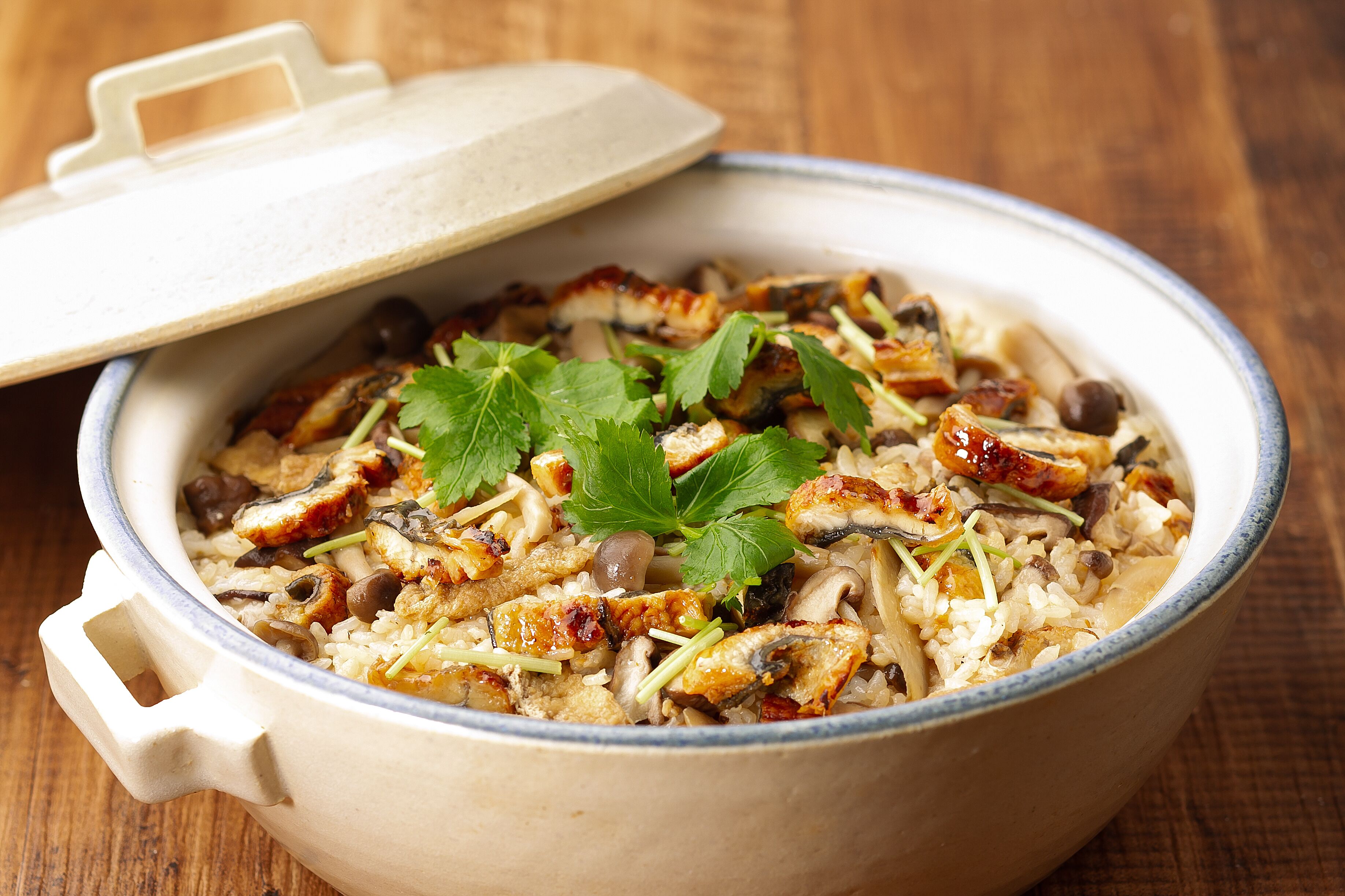 A ceramic pot with a lid, containing a rice dish with various ingredients.