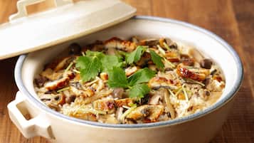 A ceramic pot with a lid, containing a rice dish with various ingredients.