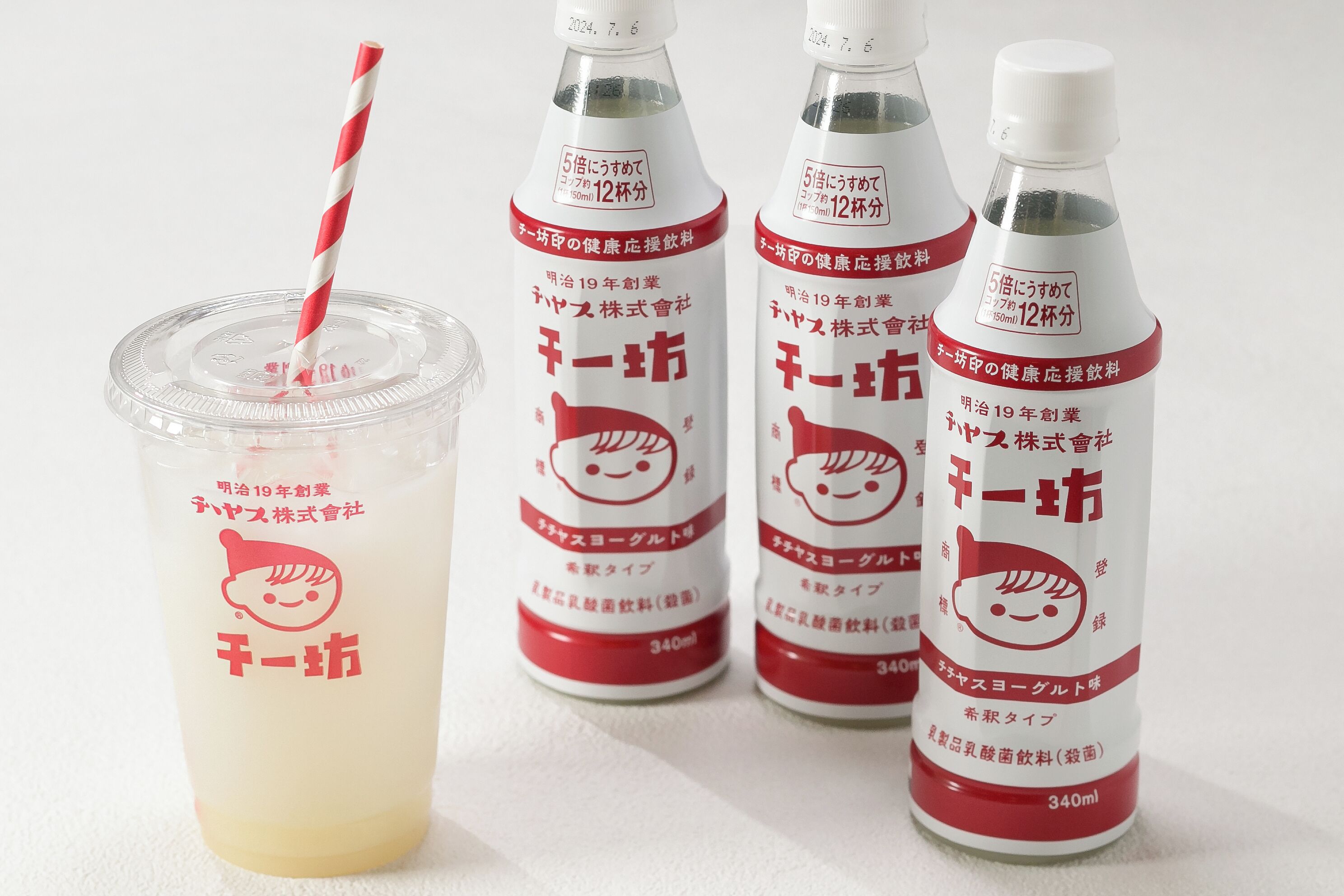 Four bottles of a beverage with a straw, one in a clear plastic cup.