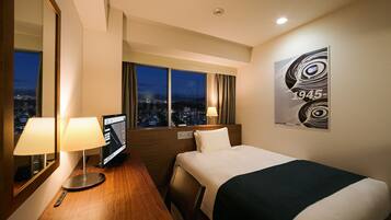 A hotel room with a bed, two bedside lamps, a flat-screen TV, a city view through large windows, and a modern abstract artwork on the wall.