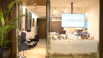Een winkel genaamd 'SHOP ORIENTAL+' met een etalagepop in een gestreepte jurk, schoenenrekken en een presentatie van tassen en accessoires.