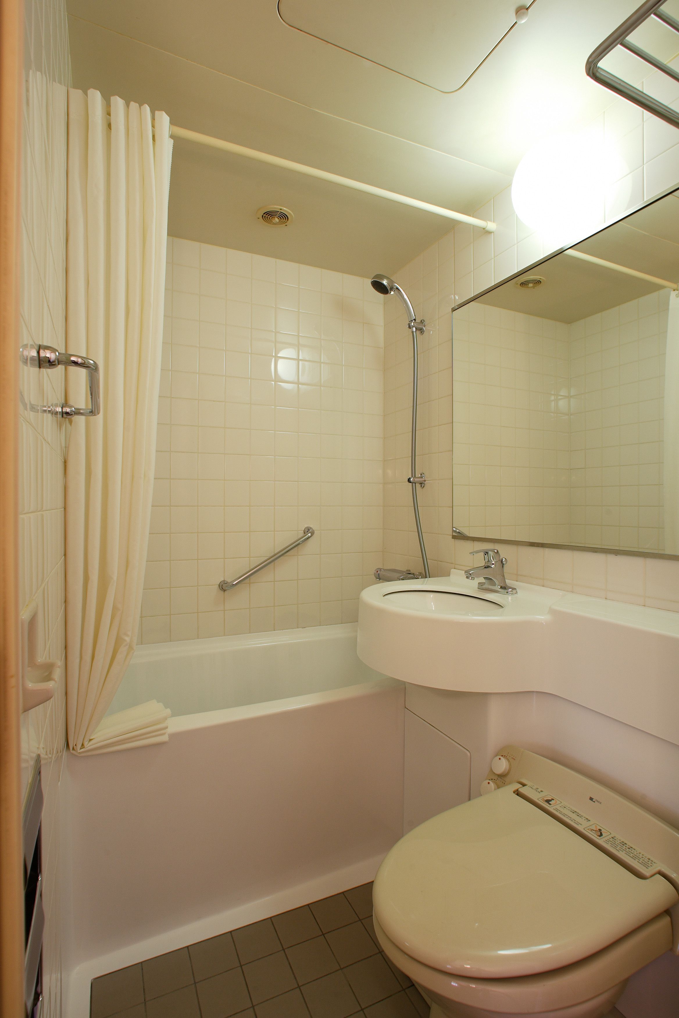 Een badkamer met een bad, toilet, wastafel en spiegel.