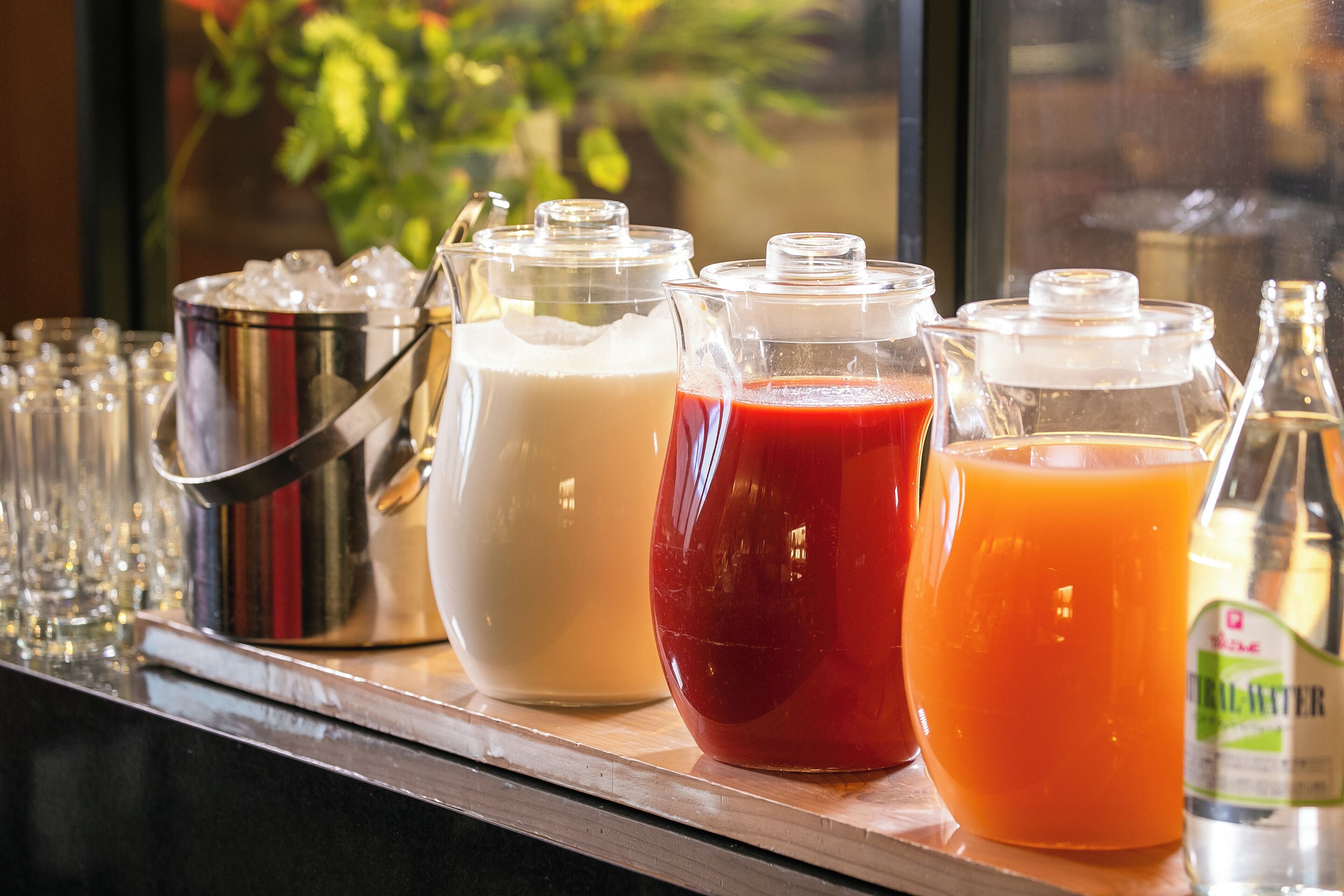 A bar area with various beverages in pitchers and bottles, including milk, red juice, and orange juice.