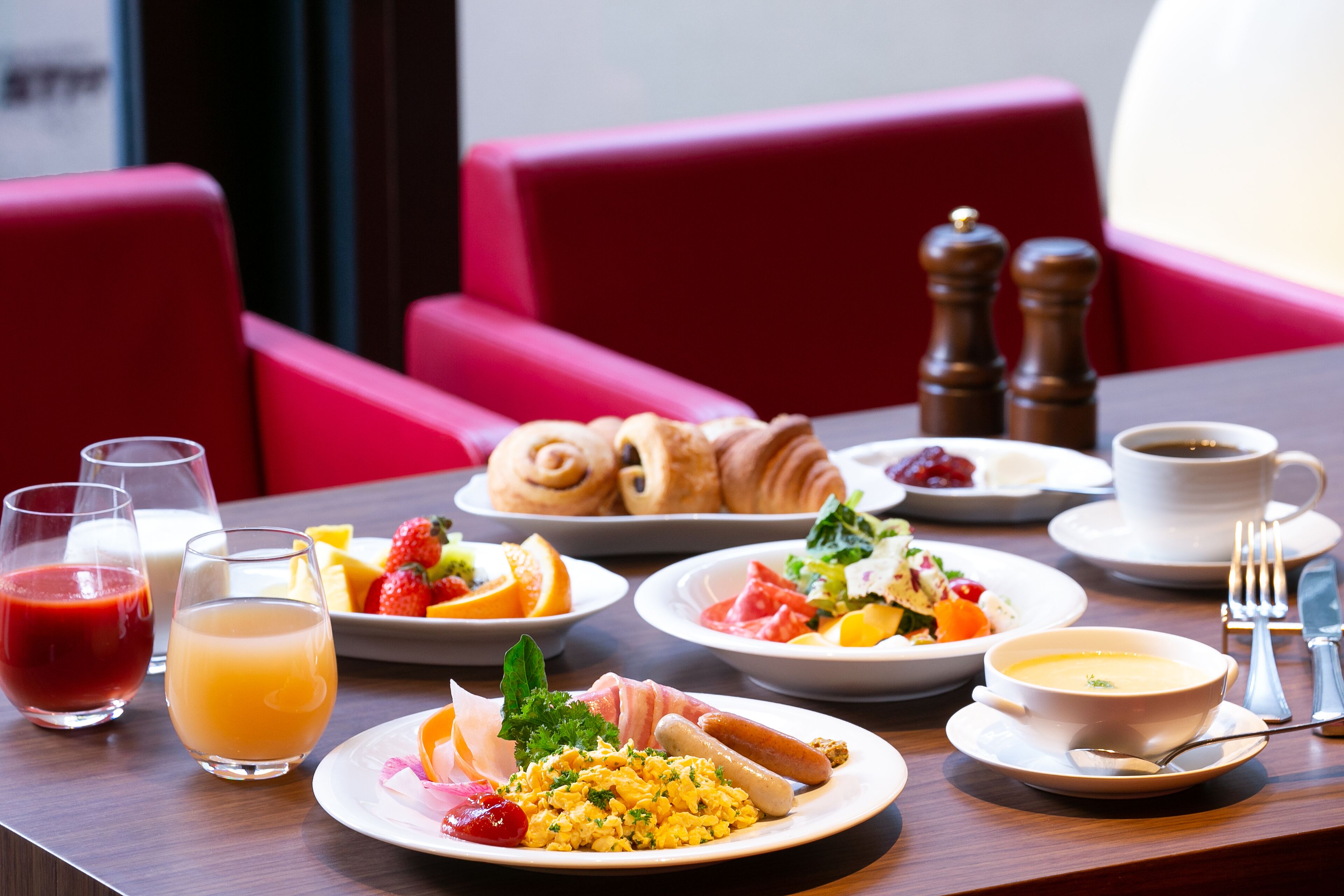 A breakfast table with plates of food, glasses of juice, and a cup of coffee.