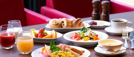 A breakfast table with plates of food, glasses of juice, and a cup of coffee.