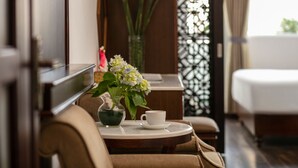 A hotel room with a bed, a small round table with a cup and flowers, and a decorative wall panel. - Victory Legend Hotel & Spa (Hanoi)