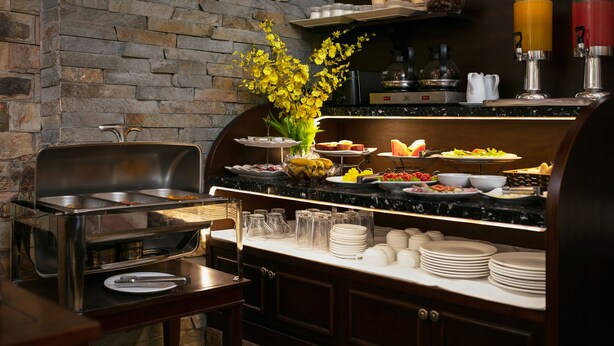 A buffet setup with various food items, a coffee machine, and a juice dispenser. - Victory Legend Hotel & Spa (Hanoi)