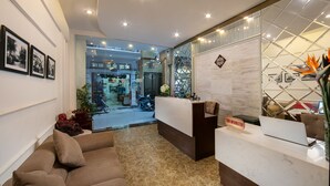 A hotel reception area with a sofa, a reception desk, and framed pictures on the wall. - Victory Legend Hotel & Spa (Hanoi)