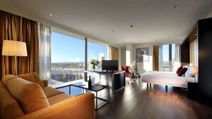 Ein modernes Hotelzimmer mit einer Couch, einem Esstisch, einem Fernseher und einem Bett.