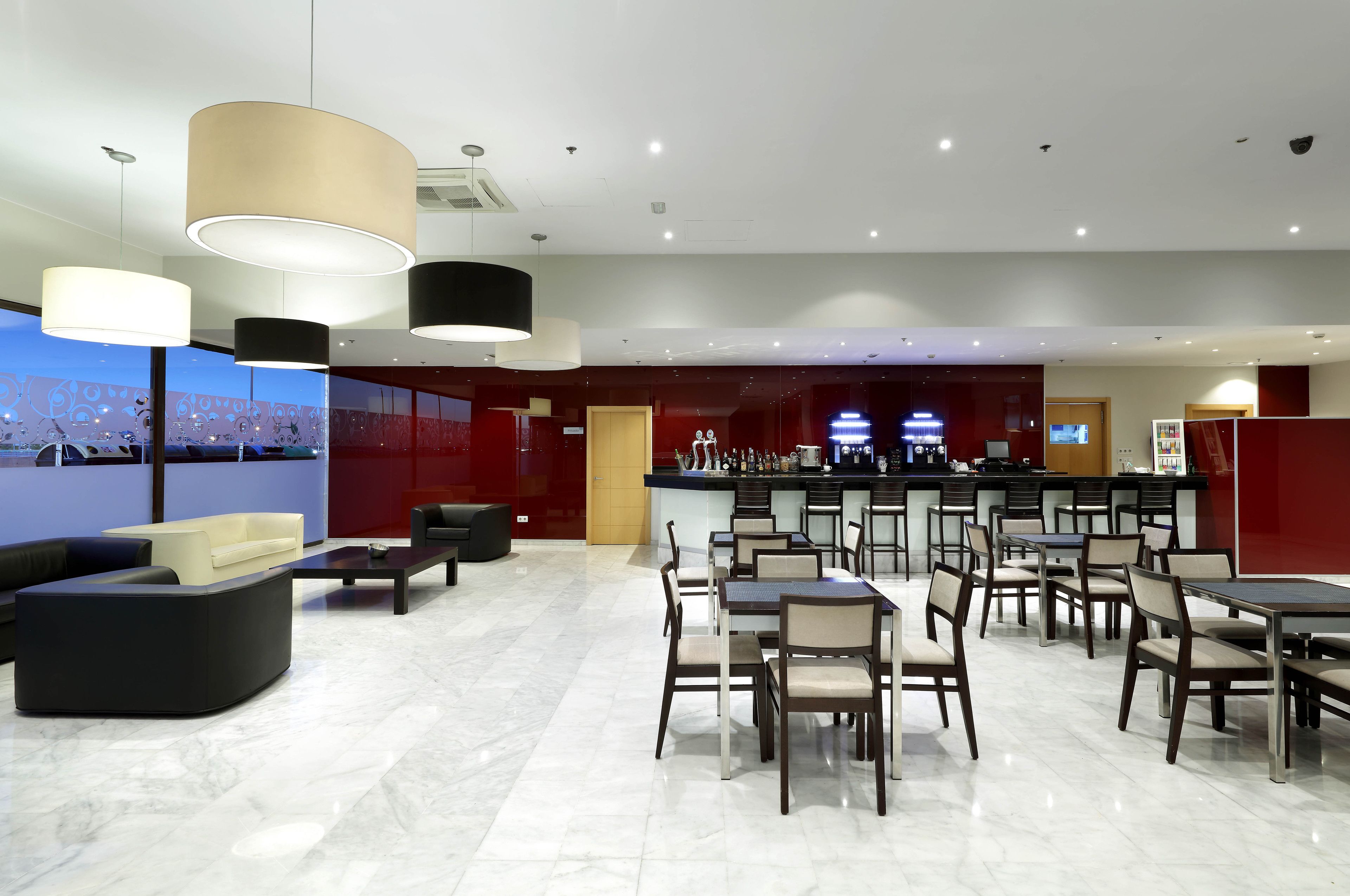 A modern hotel lobby with a bar area, seating arrangements, and a view of the cityscape.