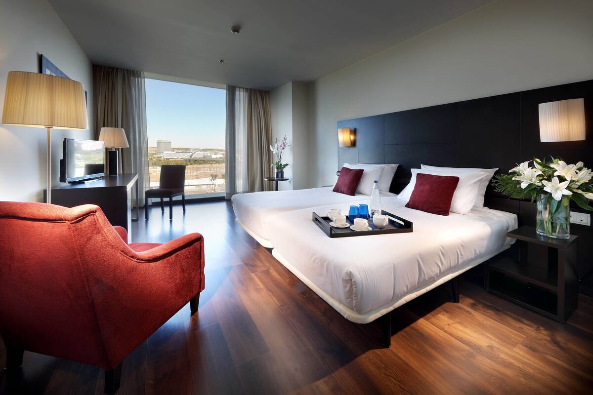Een hotelkamer met een groot bed, een bureau, een stoel en uitzicht op de stad.