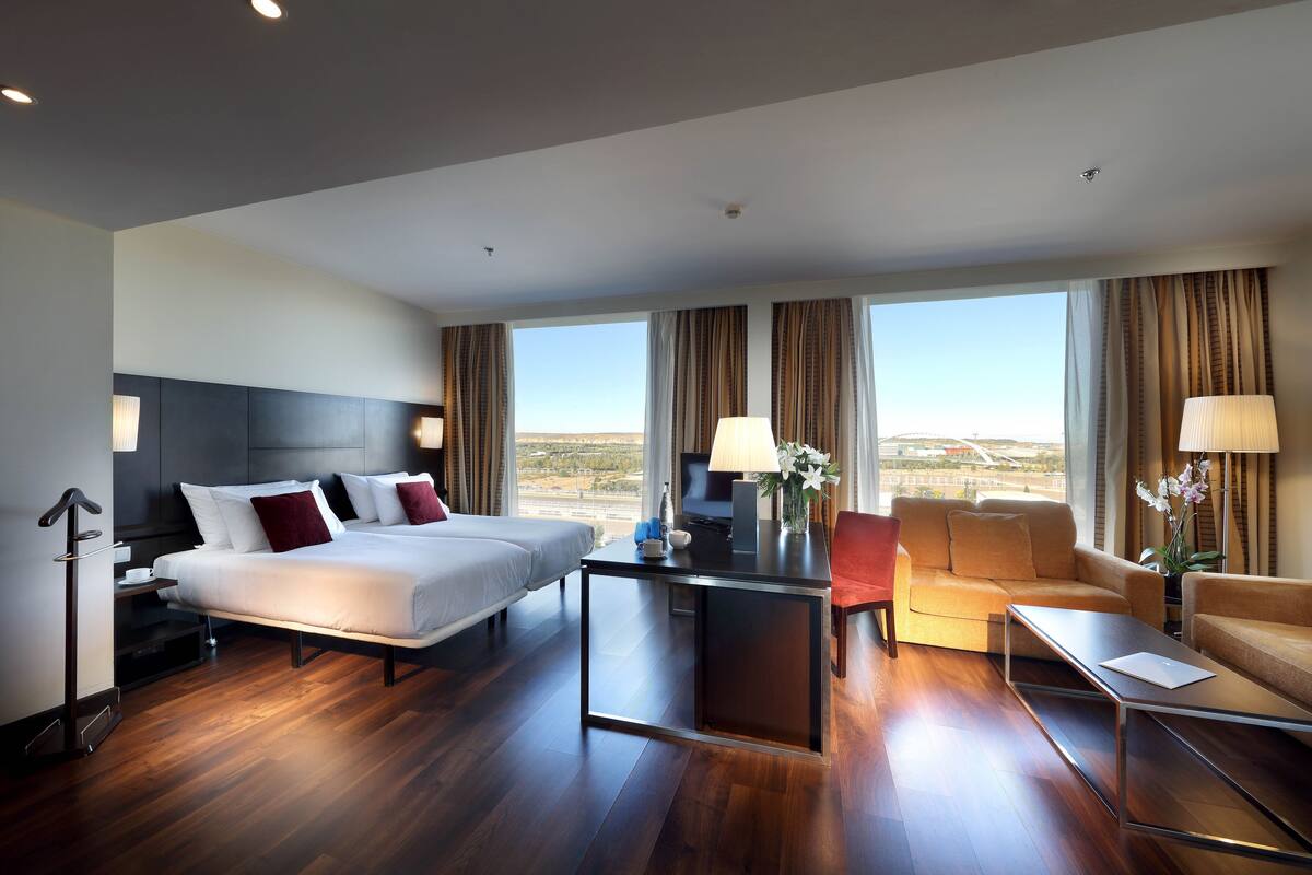 Een hotelkamer met een groot bed, een bureau, een bank en uitzicht op het landschap.