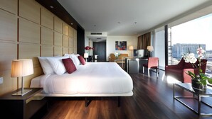 Ein modernes Hotelzimmer mit einem großen Bett, einem Schreibtisch, einem Stuhl und Blick auf die Stadt.