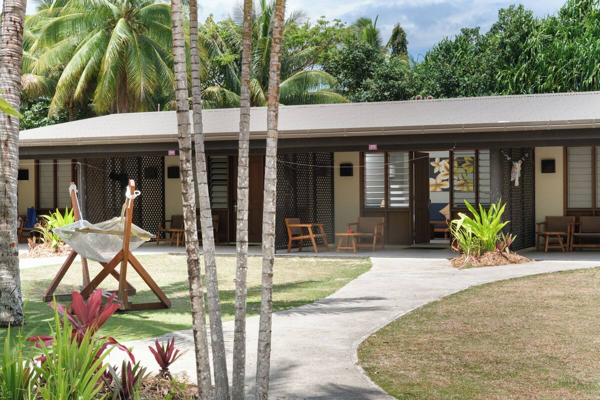 A building with a covered patio area, outdoor seating, and a pathway leading to the entrance.