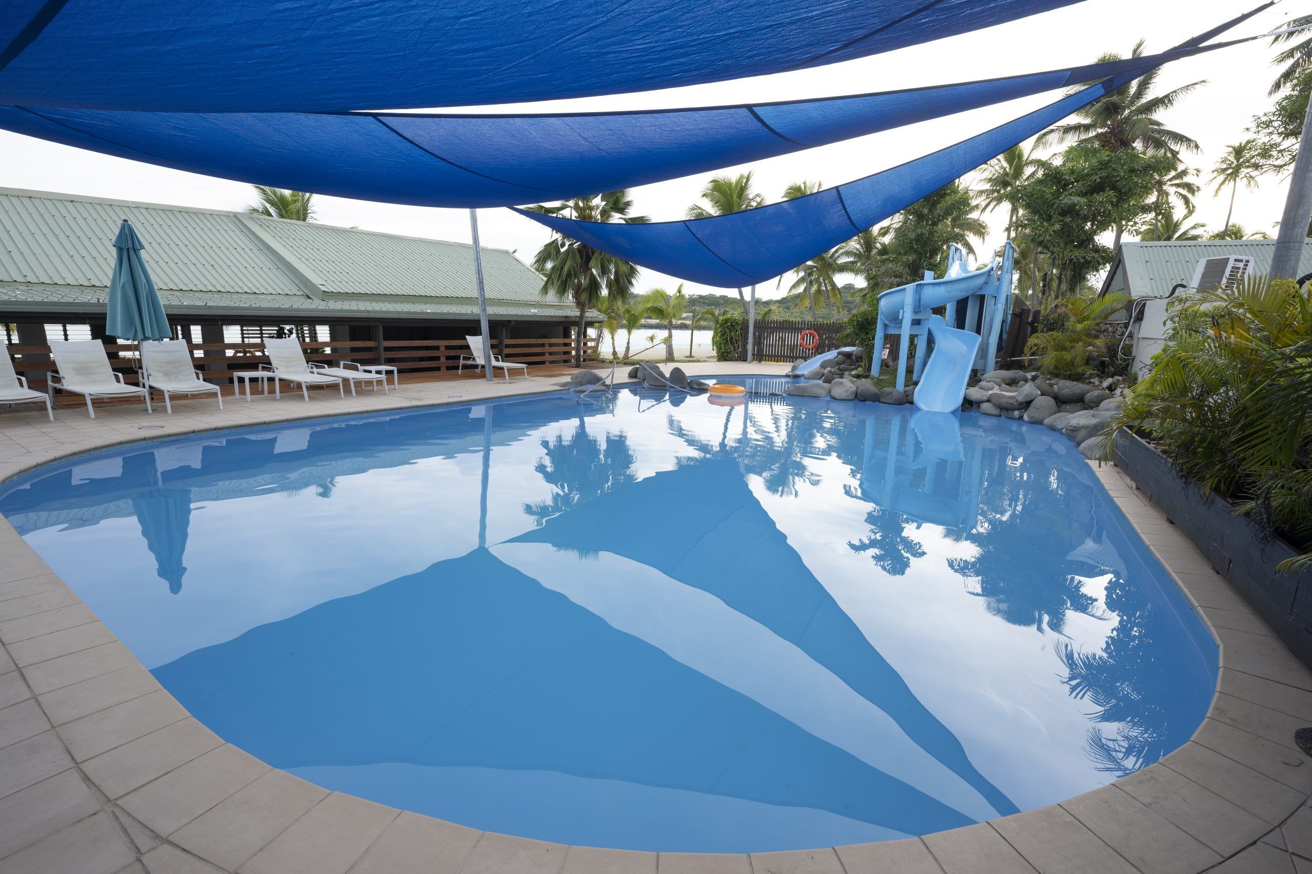 A swimming pool with lounge chairs and a shaded area.