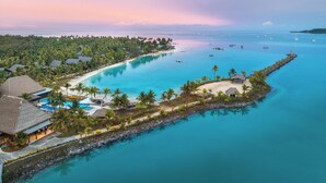 A resort with a beach, clear blue waters, and boats.