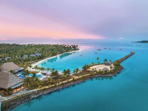 Un resort con playa, aguas azul turquesa y embarcaciones.
