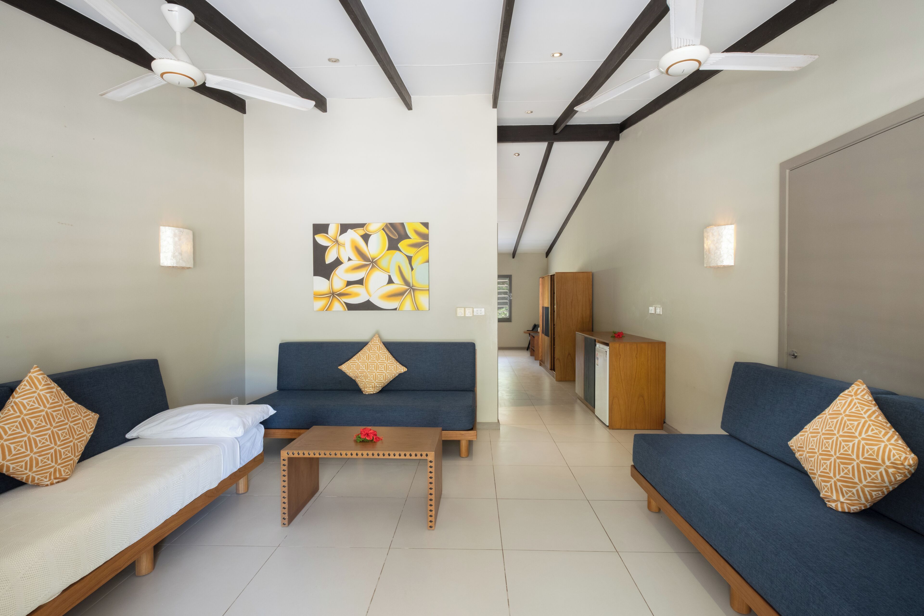 Une chambre d’hôtel moderne équipée de deux canapés, d’une table basse et de ventilateurs de plafond.