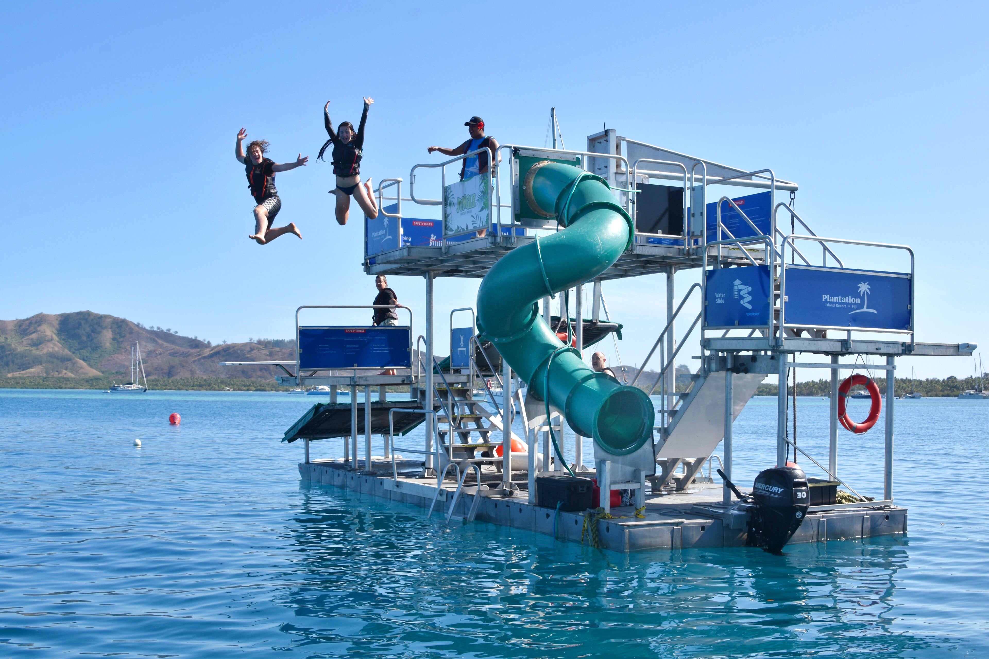 A water slide on a boat with a clear view of the water and distant hills.