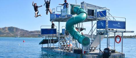 A water slide on a boat with a clear view of the water and distant hills.