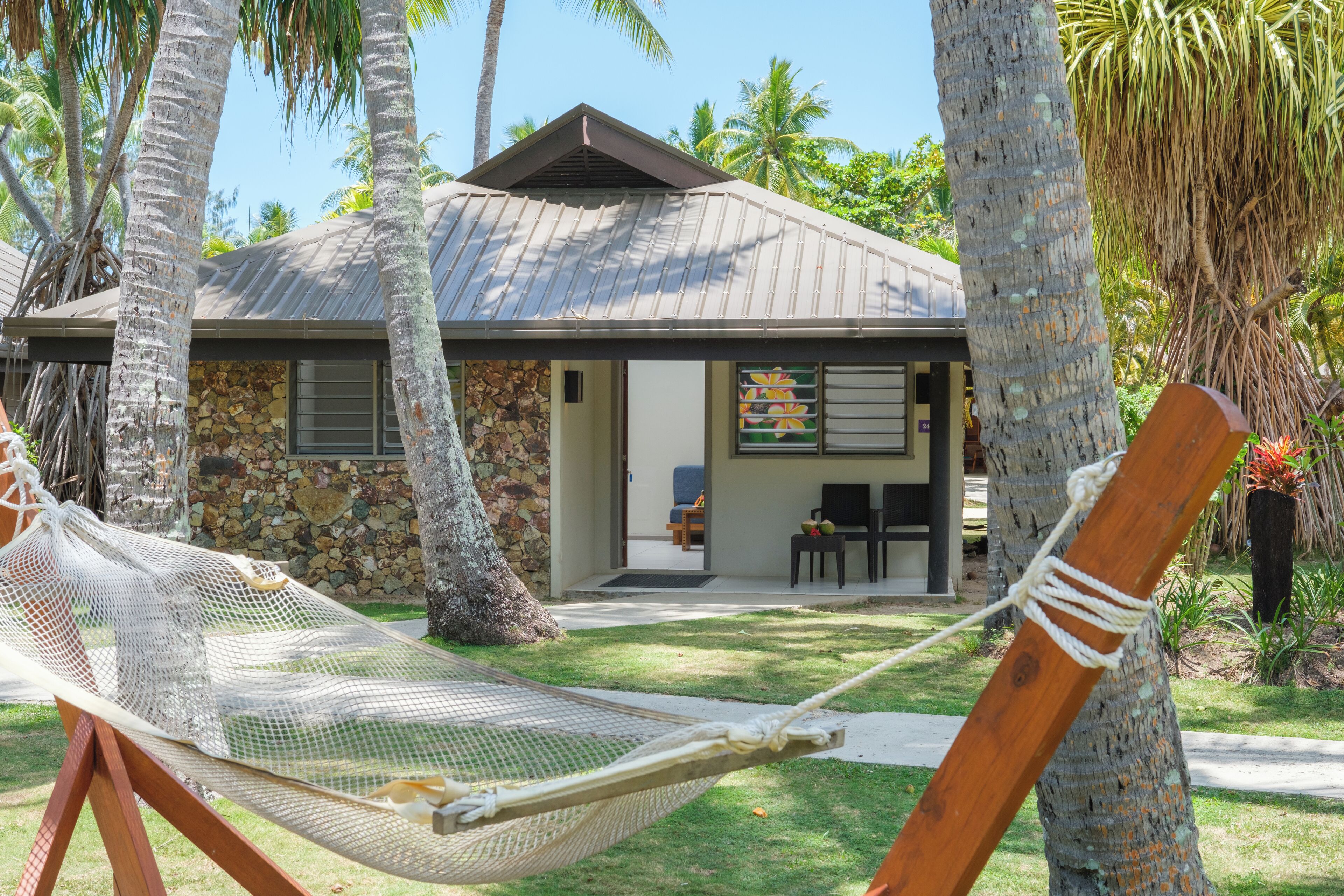 A house with a stone facade, a metal roof, and a hammock in the foreground.