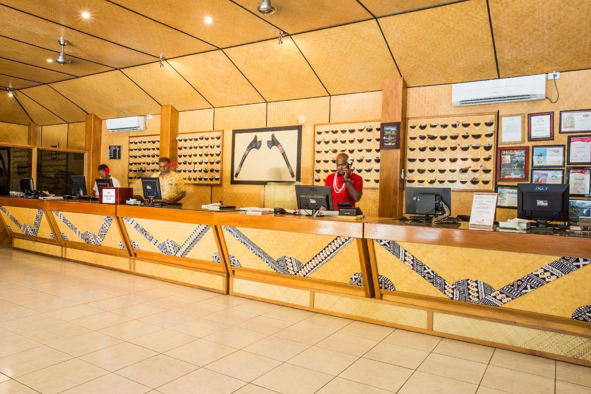 A reception area with a wooden counter, multiple computer monitors, and framed certificates on the wall.